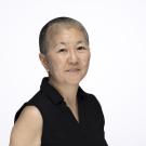 Headshot (photograph) of person with close-cropped hair, sleeveless black top, neutral expression