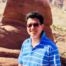 Man in striped shirt in front of a rock formation