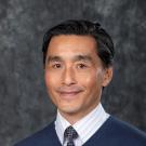 Man in blue sweater over a dress shirt and tie