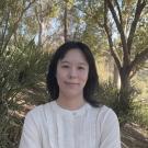 Woman in white shirt standing in front of trees